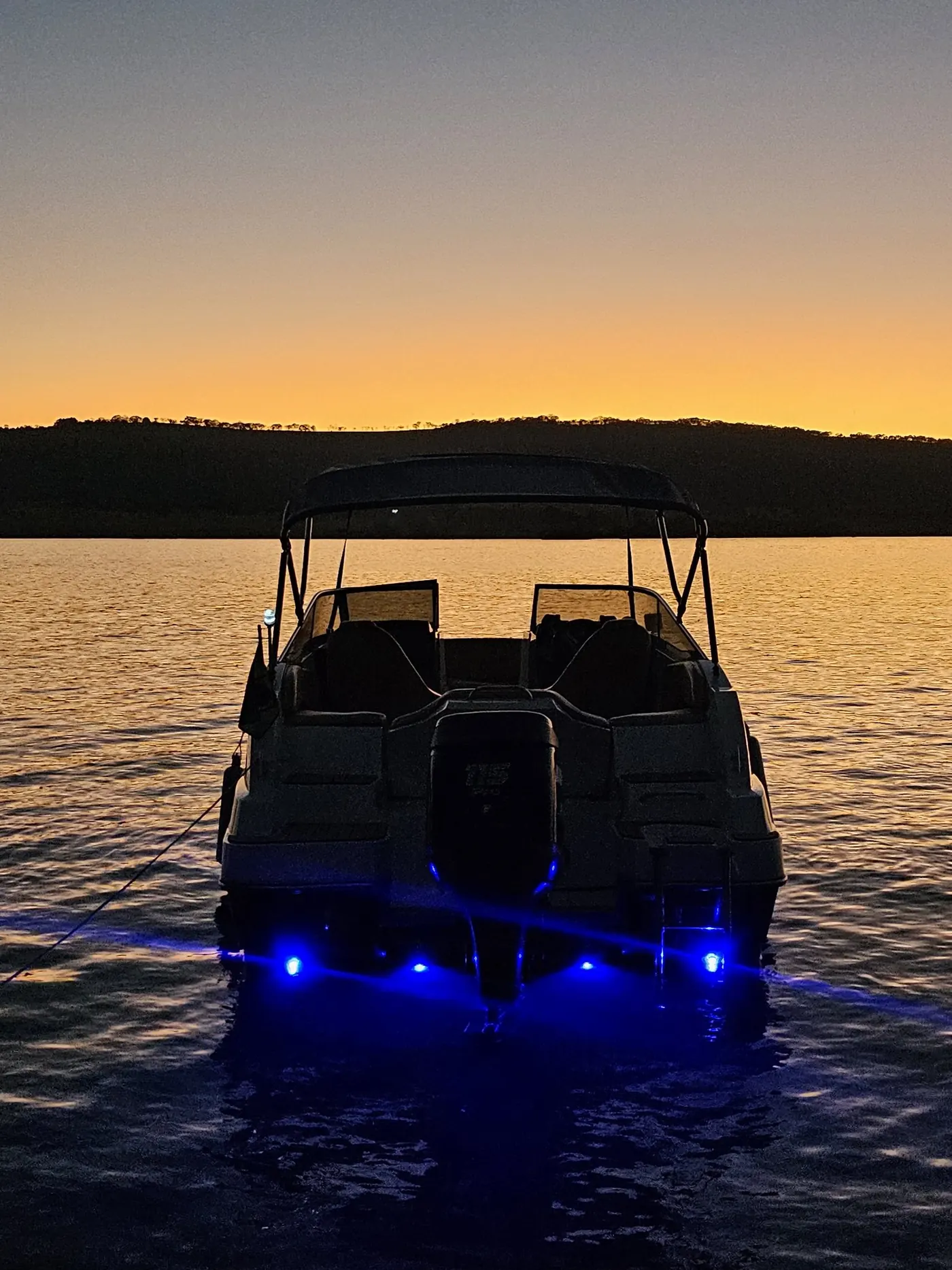 Lancha navegando ao pôr do sol com iluminação LED azul na popa